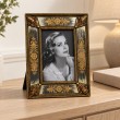 Cadre photo doré à motifs floraux de 23 cm posé sur une console en bois clair - 2